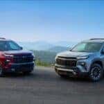 Two 2024 Chevy Traverses parked on a high cliff overlooking hills.