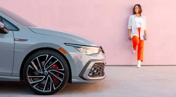 woman standing against a wall near a car
