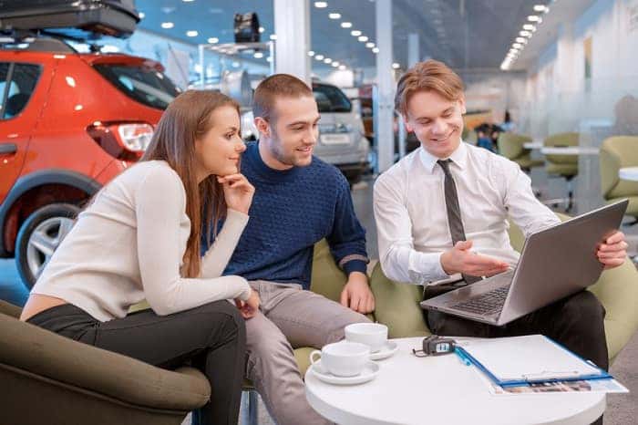 A couple speaking with a BMW financing expert to refinance their car
