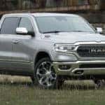 2020 Ram 1500 EcoDiesel exterior shot with gray metallic paint color parked in a grass clearing near an old and rusty bridge