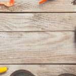a pair of fishing rods, bait, tackles, floats, and sea boots resting on a wooden fishing pier