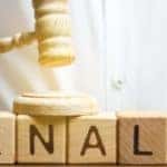 a man slamming a tiny gavel on wooden blocks spelling out penalty for a mock trial