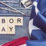 labor day written in wooden tiles upon a pair of jeans near an american flag, a wrench, nails, and an orange hard hat