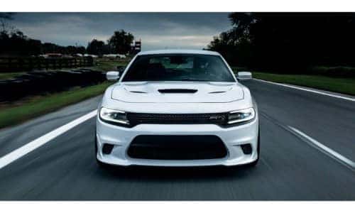 2019 Dodge Charger exterior front shot of grille, headlights, and fascia with white paint color driving down a country highway