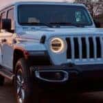 2020 Jeep Wrangler exterior front shot with white paint color and headlights on displaying iconic grille