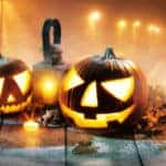 a line of spooky candle lit pumpkin jack o' lanterns surrounded by other candles, lanterns, and a lone crow for Halloween