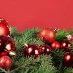 a pine tree Christmas wreath decorated with red bells and ornaments