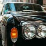 exterior closeup shot of a old luxury car grille parked on a busy downtown street