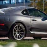 Toyota Supra coupe exterior side shot with gray metallic paint color and rear spoiler attachment