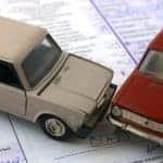 tiny car models in a collision on top of a car insurance policy term pamphlet