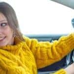 a woman looking behind her in her vehicle as she begins to parallel park her car