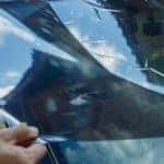 a dark tinted car film being applied to a windshield as wipers are rotated up