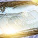 a protective reflective blanket place across the windshield of a blue car to absorb and reflect heat and sunlight