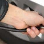 an auto mechanic checking and fixing tire pressure in a car model