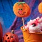 a bucket full of Halloween decorations, treats and candy with a winking plastic pumpkin in the background