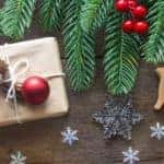 tree branches, fruit, snowflakes, presents, and more Christmas decorations on a wooden table