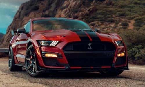 2020 Ford Mustang Shelby GT500 exterior front shot of grille and headlights with red paint color and racing stripe down hood