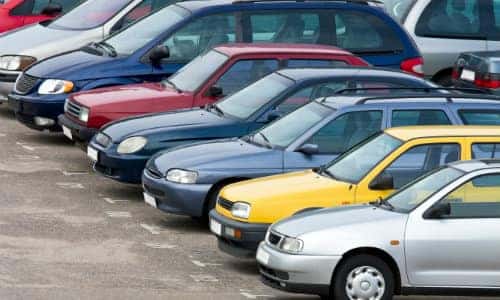 a row of colorful cars parked outside of a pre-owned automotive car dealership