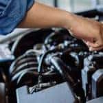 a mechanic in a jumpsuit working on an engine under a car hood