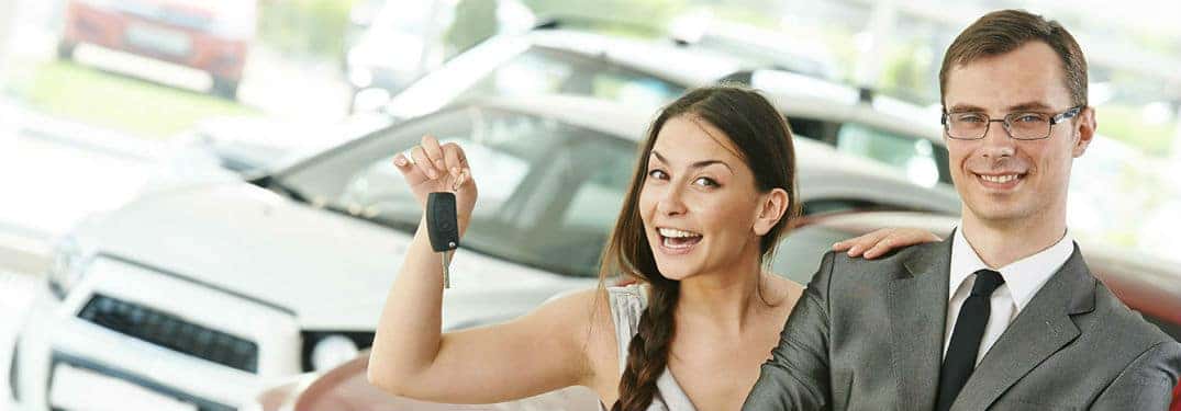 Two people standing in front of a car
