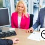 Car Salesman Talking with a Couple at a Desk with Carl Black Hiram Logo