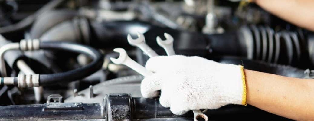 white-gloved hand holding three tools