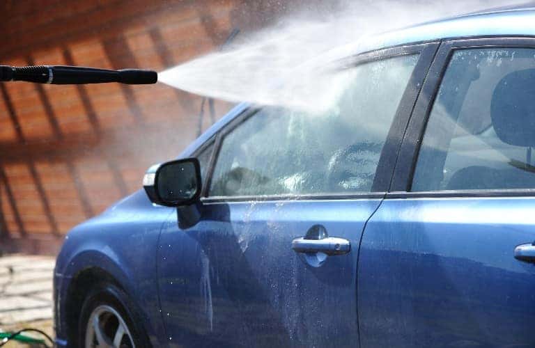 a blue car being sprayed by a hose
