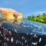 a hand washing a car with a sponge