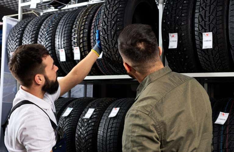 two men standing by a rack of tires