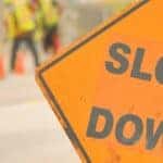 An orange slow down sign by a road