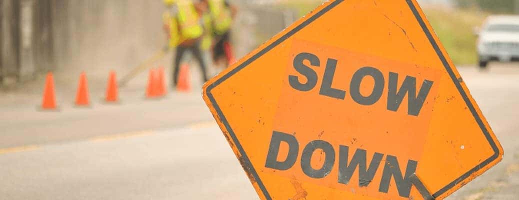 An orange slow down sign by a road