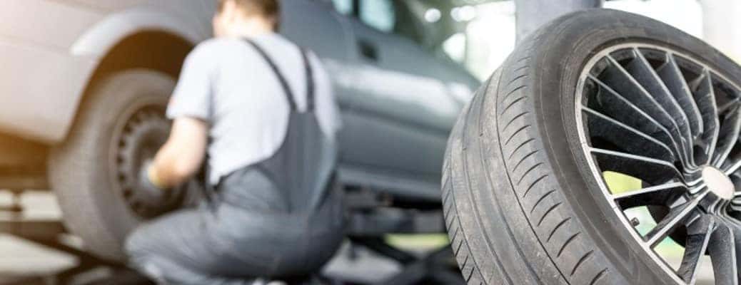 a man kneeling by a car replacing a tire