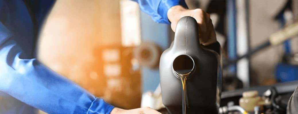two hands pouring oil into an engine