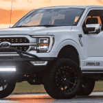 a white lifted Ford truck in front of an orange sunset