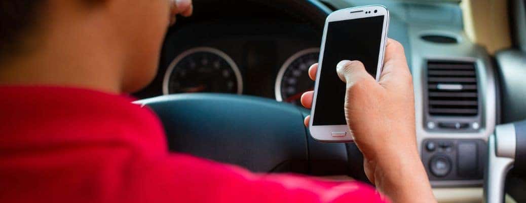 a person in a red shirt holding a white phone in a vehicle