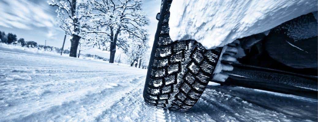 a close up of a tire driving through snow