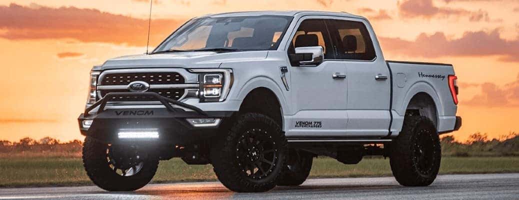 white lifted Ford truck in front of an orange sky