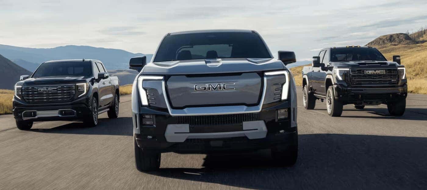 Front exterior action shot of the GMC Sierra truck family driving together down a remote highway.