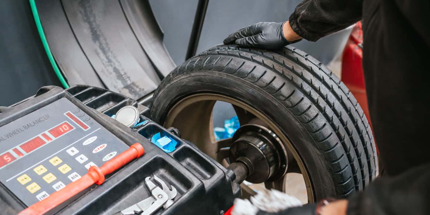 Wide shot of a man pulling a tire from a row of tires on a rack to inspect it.