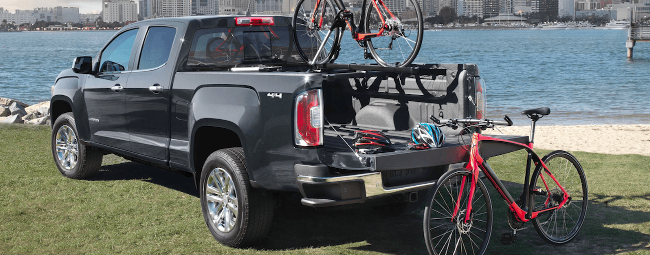 Black 2019 GMC Canyon unloading bikes near city river