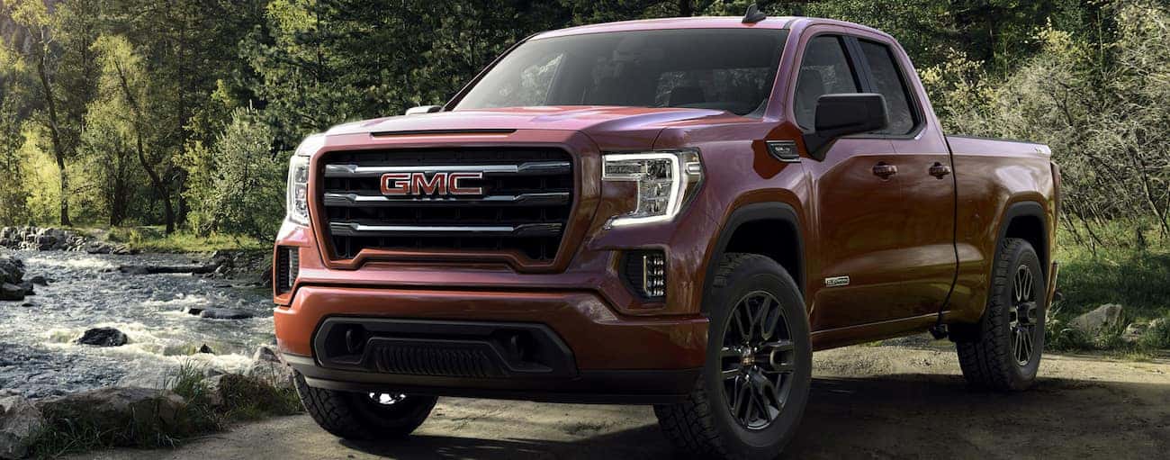 A bright red 2019 GMC Sierra parked next to a fast moving river
