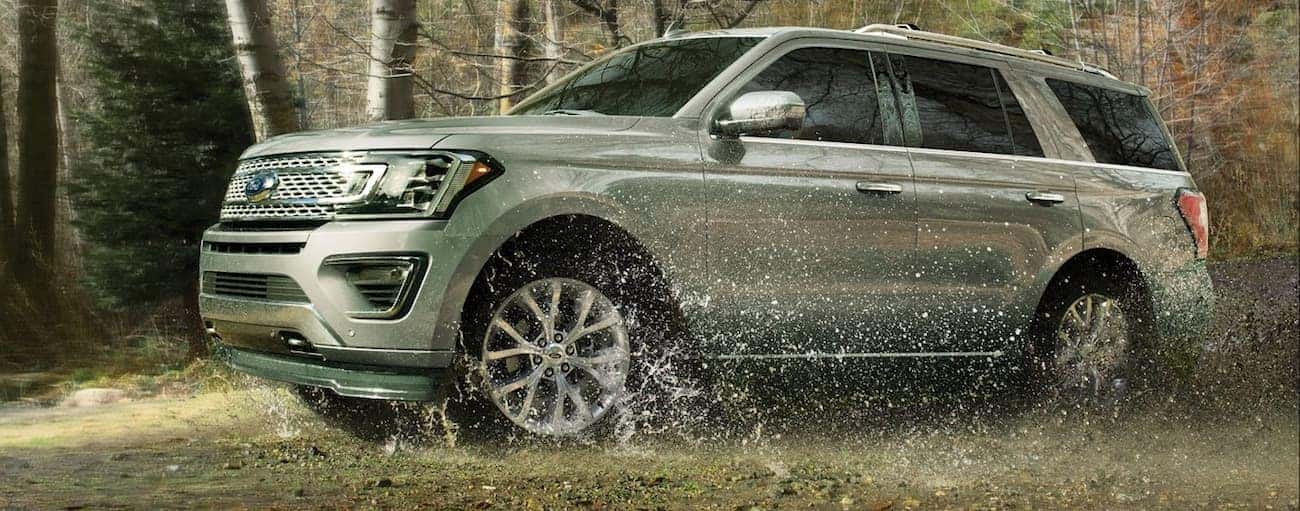 Silver 2019 Ford Expedition driving through mud in woods