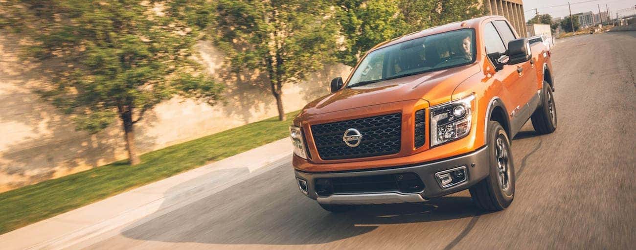 Orange 2019 Nissan Titan driving on tree lined road