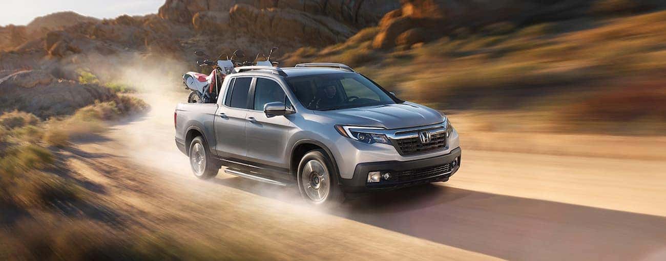 Silver 2019 Honda Ridgeline in desert with dirtbikes in bed