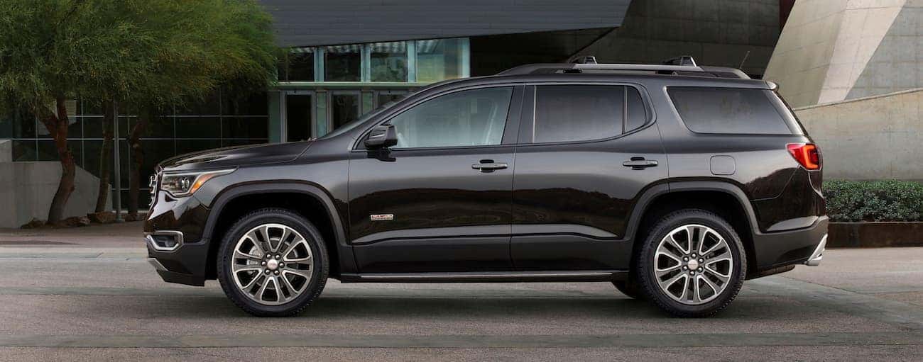 A black 2018 GMC Acadia All Terrain parked in front of a museum-looking building
