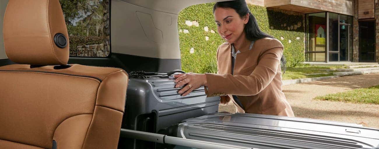 A woman loading cargo into the back of a 2019 GMC Acadia