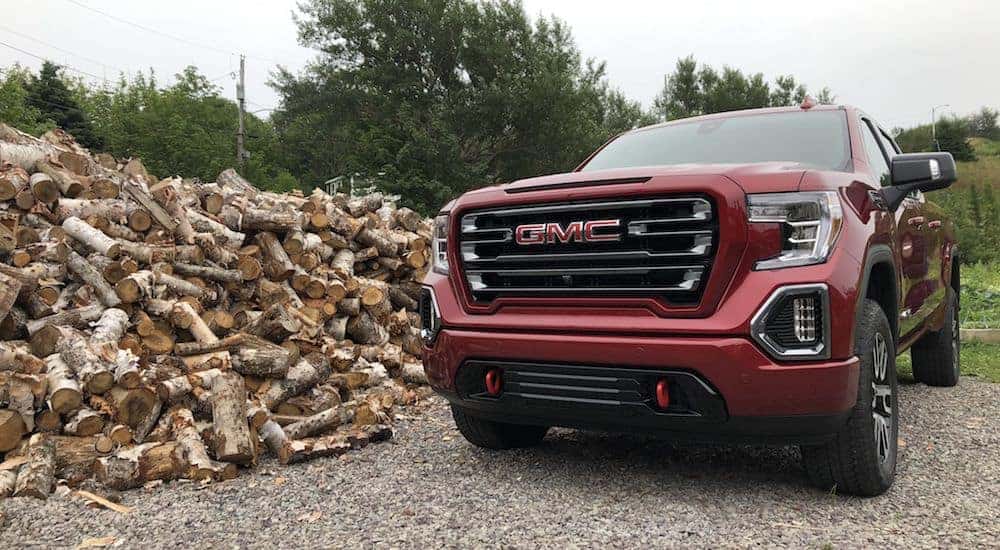 A red 2019 GMC Sierra next to a giant pile of wood