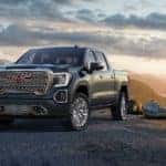 A gray 2019 GMC Sierra Denali on a mountain edge at sunset
