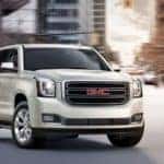 white 2019 GMC Yukon driving through downtown
