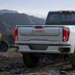 2020 GMC Sierra AT4 exterior back fascia and passenger side on hill with ATVs next to it